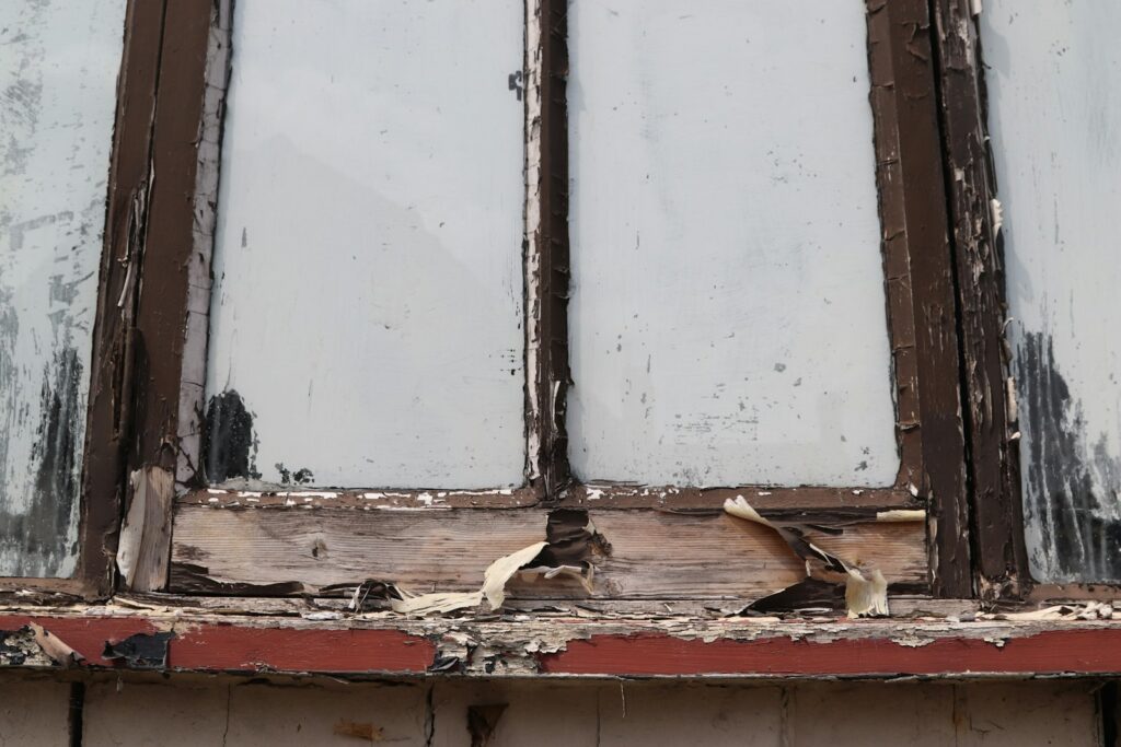 Damaged window frame with peeling paint, the sort of wear that can come with a faulty sash