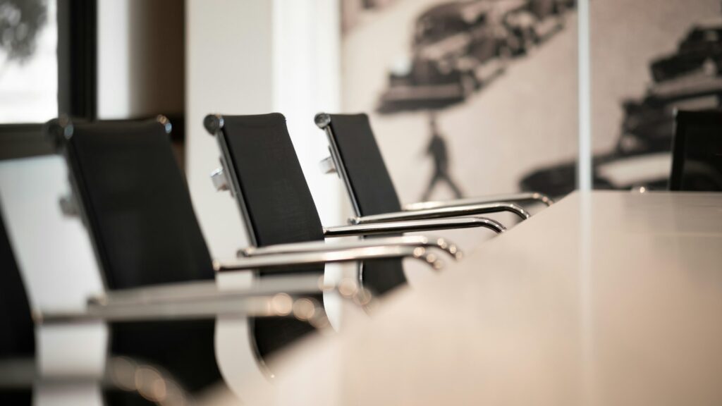 Black office chairs with chrome arms lined up along a conference table, ready for a team meeting