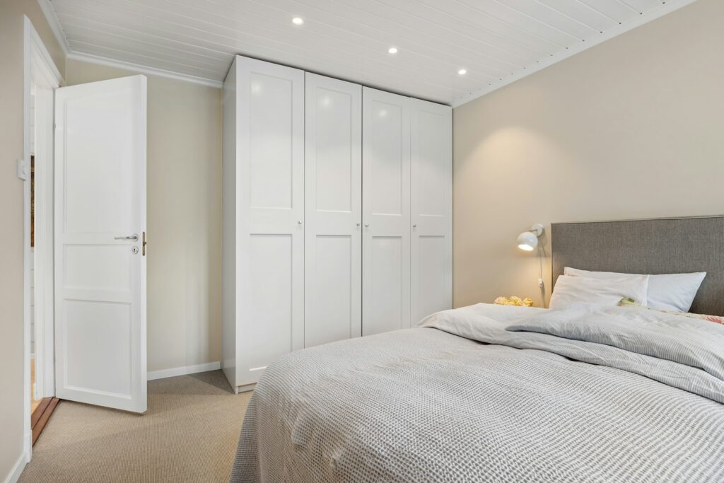 Bedroom with a large bed and white cupboards, a calm setting for updated wardrobe doors