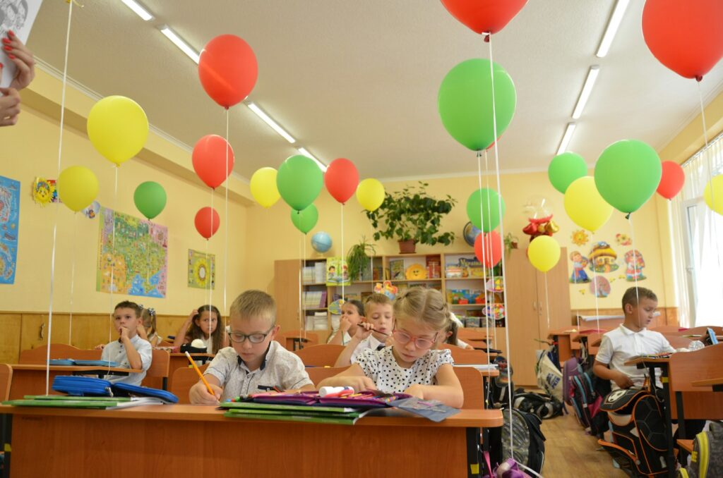 Children learning in a classroom decorated with colourful balloons, showing school life that a website could convey