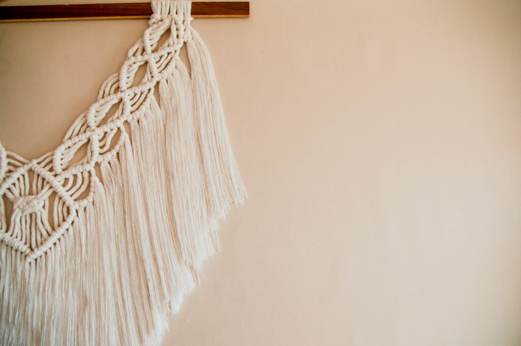 White cotton macramé wall hanging with rope knots displayed against a white wall