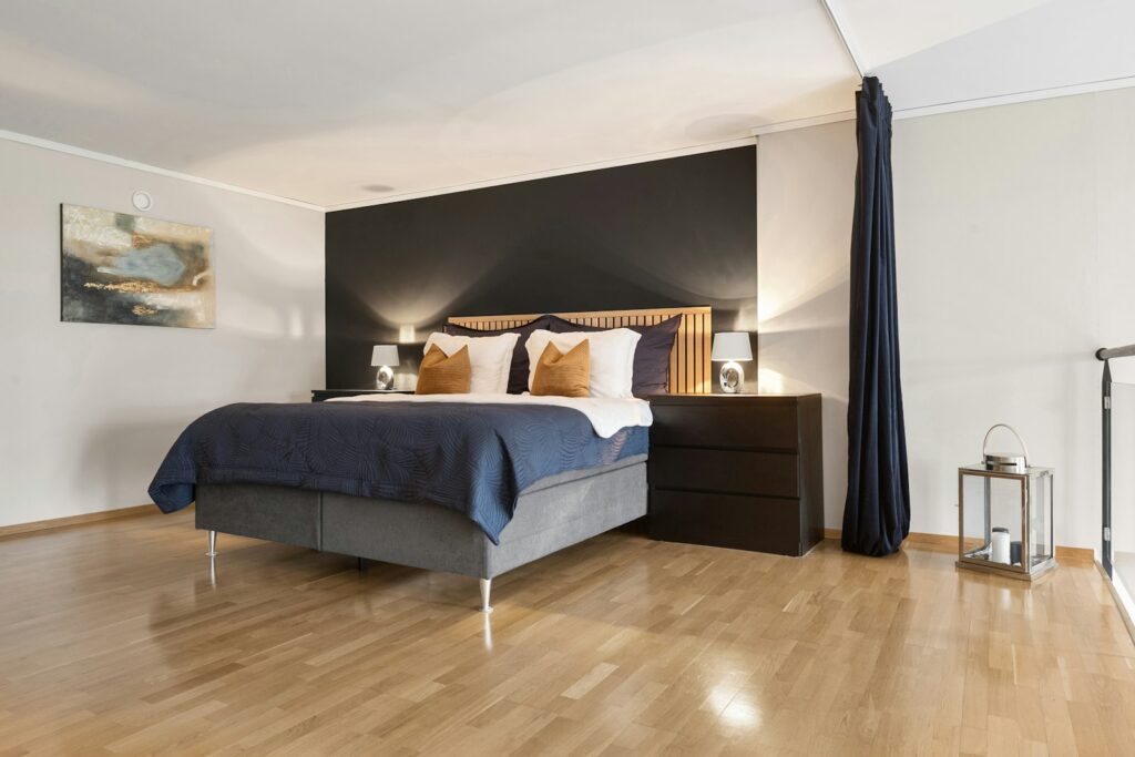 Bedroom with hardwood floors and a large bed, showing how floor colour shapes the room