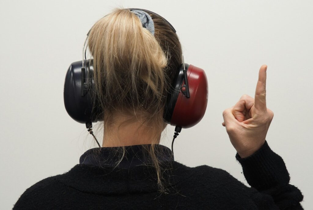 Woman wearing headphones and pointing to the side during a hearing test